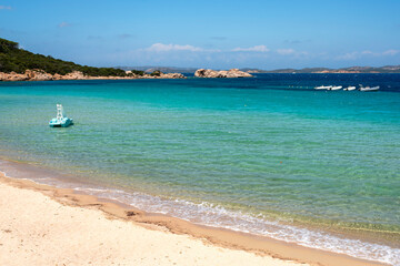 Obraz premium View of the beach of Baia Sardinia, a tourist resort in northern Sardinia Island, famous for the clarity of the sea waters and the beauty of the surrounding landscape.