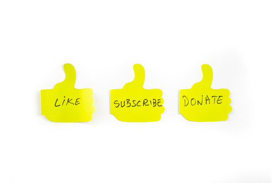 Like, subscribe and donate words written on sticky notes of the shape of thumbs up hand, isolated on white background