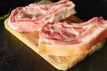 Pieces of raw pork meat lie on a wooden board. Meat production