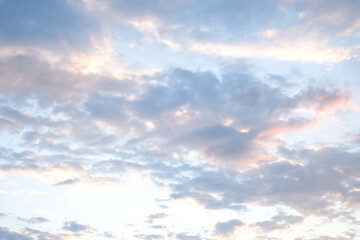 Fototapeta premium Soft blue sky combined with light of sunset creates peaceful sky. Beautiful landscape with clouds and orange sun. Sky overhead: creamy clouds in pastel colors.