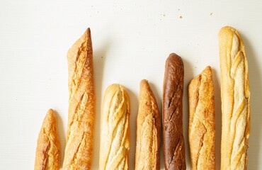 Baking, sourdough bread, dough products, flour, gluten flatlay. A variety of loaves, French baguettes, bread in a craft paper bag on a white background, copy space