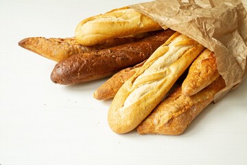 Baking, sourdough bread, dough products, flour, gluten. A variety of loaves. French baguettes, bread in a craft paper bag on a white background, copy space