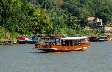 Sunset cruise along the Mekong River on traditional boats transformed into a boat for tourists in Luang Prabang, Laos,