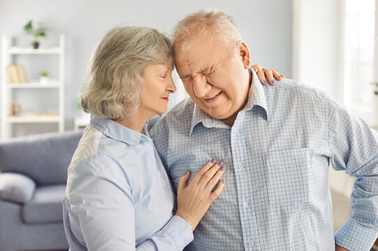 Tired upset mature old man suffering from strong chronic ache at home, wife supporting him close, stressed dizzy fatigued senior person feels bad pain, backache radiculitis getting kind help and care - Powered by Adobe