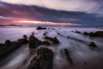 Sunset with clouds on Barrika beach with the tide between the flysch