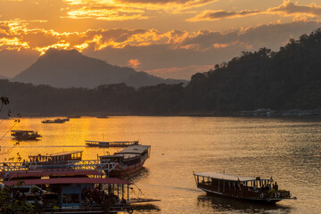 Sunset cruise along the Mekong River on traditional boats transformed into a boat for tourists in Luang Prabang, Laos,