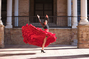 Young, beautiful, brunette woman in black shirt and red skirt, dancing flamenco between marble columns in Spain square in Seville. Flamenco concept, dance, art, typical Spanish. © Manuel