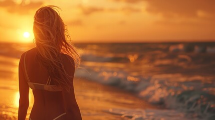 A woman walks on the beach at sunset