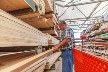 Fototapeta premium Retired Hispanic man in his 70s selecting wood to buy at the store to make renovations to his house
