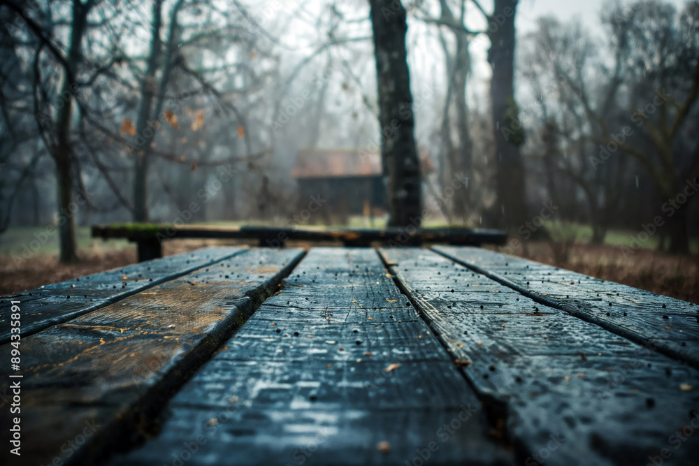 Aufkleber wet wooden picnic table surface with raindrops, blurred background of a forest and wooden house on a