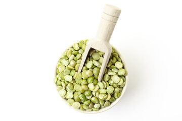 Dry, green peas in bowl with wooden scoop on white background. Top view