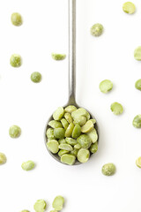 Dry, green peas in iron spoon on white background
