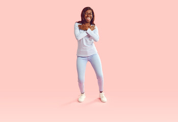 Positive African American young woman dancing with exuberance isolated a pink background. Her...