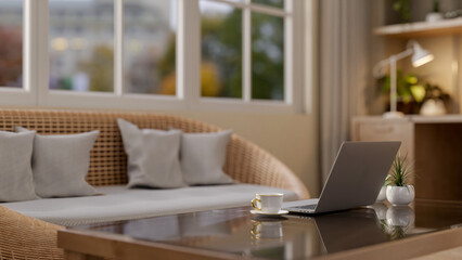 A laptop computer on a modern coffee table in a cozy contemporary apartment living room.