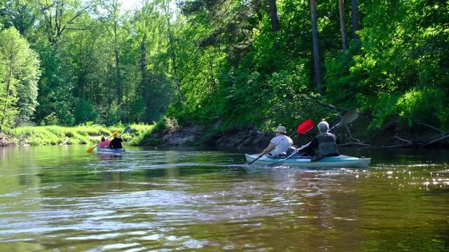 Family kayak trip for seigneur and senora. An elderly married couple rowing a boat on the river, a water hike, a summer adventure. Age-related sports, mental youth and health, tourism, active old age
