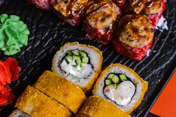 Japanese food: sushi and a variety of rolls on a black plate. Japanese restaurant menu, sushi delivery. Selected focus