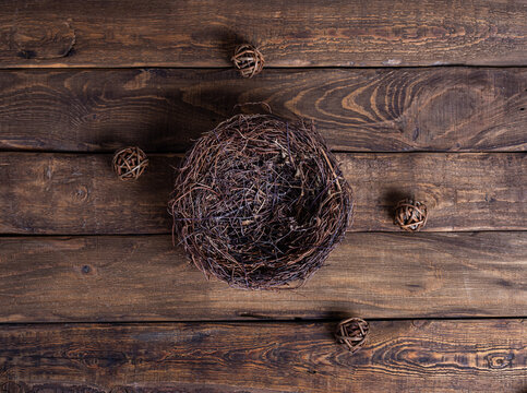 Nest with decorative brown straw ball on brown wooden background, eggs, domestic concept