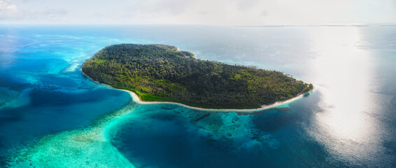 An aerial view of Sumatra's island Sikandang, showcasing the stunning contrast between lush tropical forests and vibrant turquoise waters. A paradise waiting to be explored.
