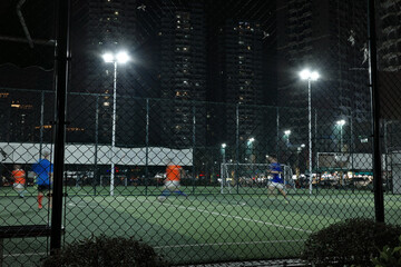 People playing football on outdoor football field at night