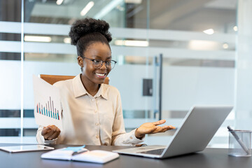 Confident businesswoman holding chart data during video conference meeting. Concept of remote work, business communication, and modern technology in workplace.