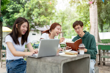 A group of positive Asian college students is working on a co-project together at a table in a park.