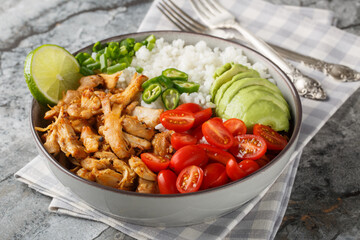 Rice bowl with pulled chicken carnitas, cherry tomatoes, avocado, peppers close-up on the table. Horizontal