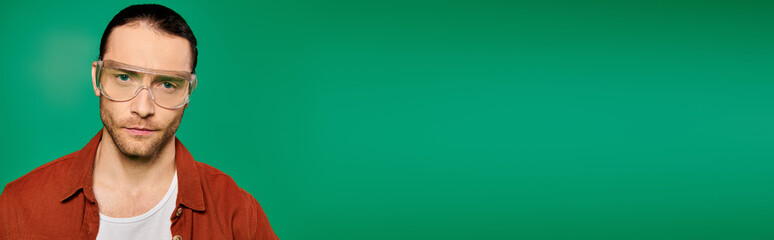 Fototapeta premium A man wearing glasses poses against a vivid green background.