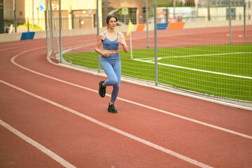 Fototapeta premium woman in blue sportswear runs on a track, demonstrating focus and endurance. This image highlights the importance of cardiovascular exercise for maintaining fitness and overall health.