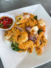 Omelette with shrimp and seafood on rice and sauce on white ceramic plate and spoon and fork.