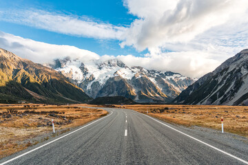 Naklejka premium Road trip with asphalt road leading to Mt Cook with snow capped among grassland in national park at New Zealand