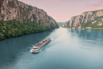 Aerial view of a cruise ship traveling through the Danube River's Iron Gate between Serbia and...