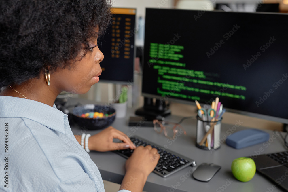 Poster side view of young african american software developer typing on keyboard while writing code for app