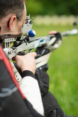 A determined male athlete practices for an upcoming competition with a free rifle, known for his focus, precision, and commitment to excellence in sports shooting.