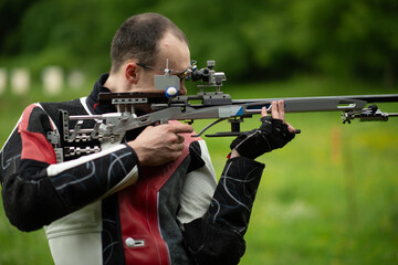 Fototapeta premium A skilled male athlete engages in free rifle training outdoors, demonstrating his expertise and precision in shooting, known for his dedication and focus in the open-air practice environment.