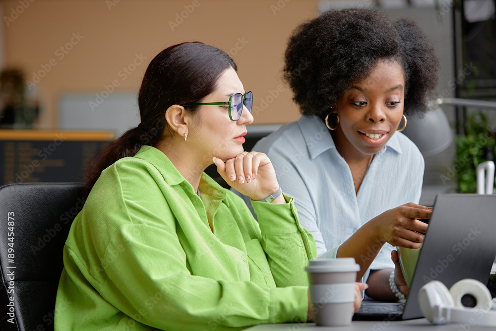 Poster young smiling african american woman pointing at computer screen while assisting higher-weight junio
