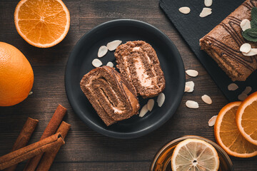 Roll cake in a bowl with fresh oranges on a dark background