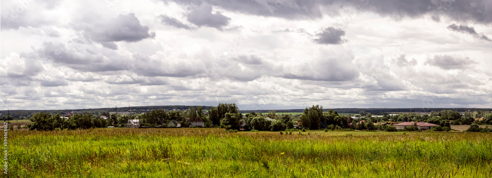 Wall mural panoramic view of a rural landscape with a green meadow