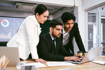 Diverse colleagues Asian and Caucasian working group meeting on project together, using laptop, sitting in office, discussing strategy and brainstorming. Multiracial business people in meeting concept