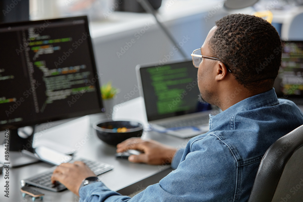 Aufkleber back view of male african american it engineer focused on writing code looking at computer screen on