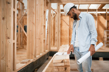 Architect is with plan of the building. Industrial worker in wooden warehouse