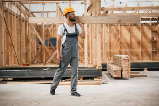 Going and carrying plank. Industrial worker in wooden warehouse