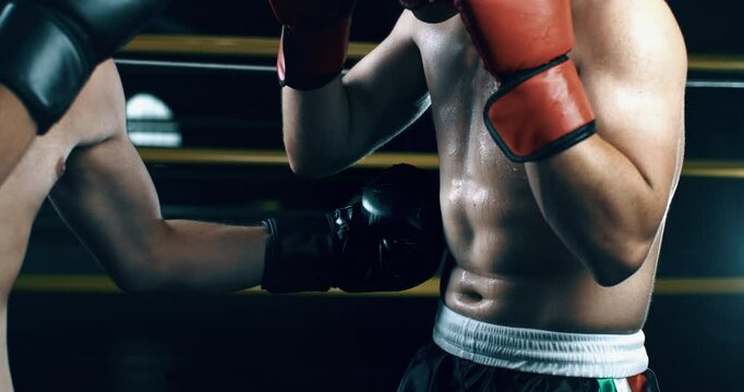 Super slow motion close up of determined young sporty muscular shirtless male boxers fisting and punching boxing workout training to achieve victory on competition at fighting ring at 1000 fps.