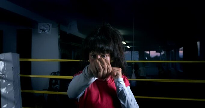 Super slow motion close up of determined sporty female athlete is doing fisting and punching boxing workout training to achieve victory on competition at boxing ring at 1000 fps.