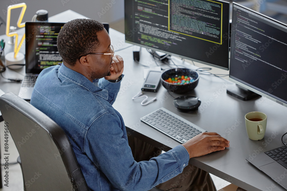 Poster high-angle side view of thoughtful male african american software developer reading computer screen 