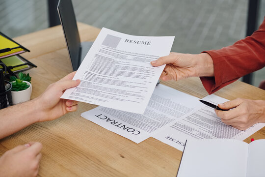 A man hands a resume to a woman during a job interview.