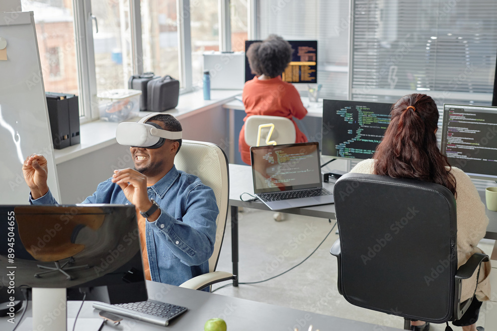 Poster wide angle shot of cheerful male african american software developer in headset testing vr applicati