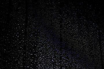 Many white drops in bokeh on a black background