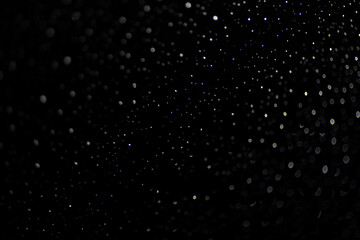 Many white drops in bokeh on a black background