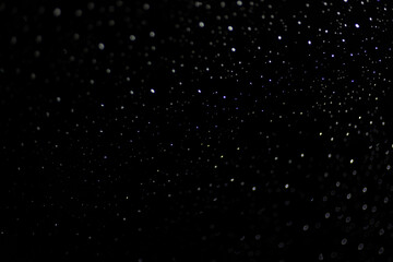 Many white drops in bokeh on a black background