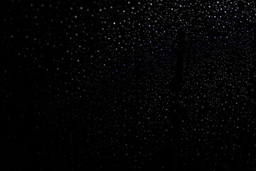 Many white drops in bokeh on a black background